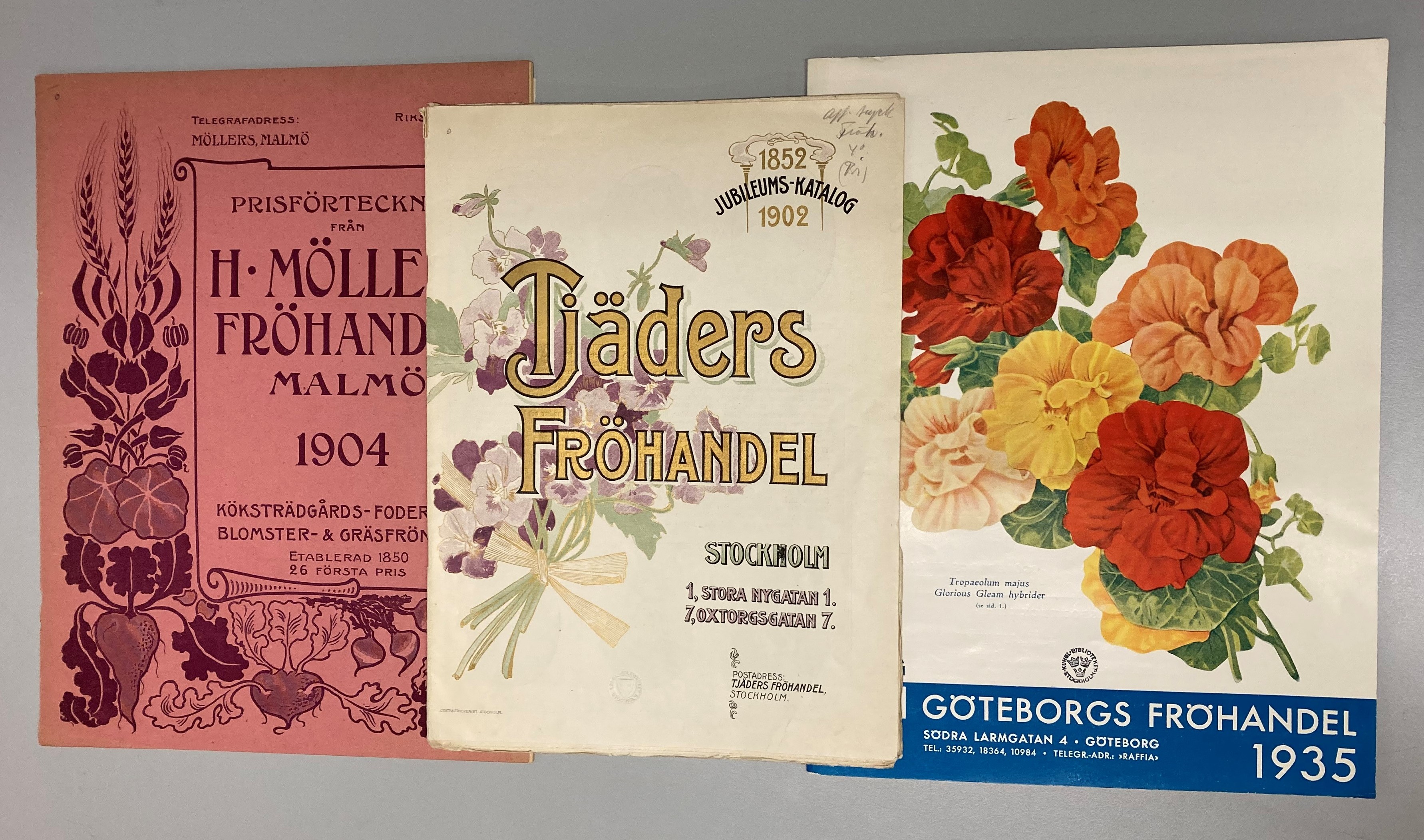 Färgfotografi av tre färgglada tryckta fröhandelskataloger illustrerade med blommor.