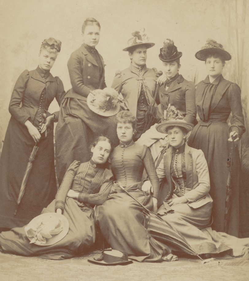Fotografi taget 1891 som visar åtta kvinnor i långa klänningar och flera bär tidstypisk hatt. Kvinnorna är studenter vid Uppsala universitet och i mitten längst står Lydia Wahlström.