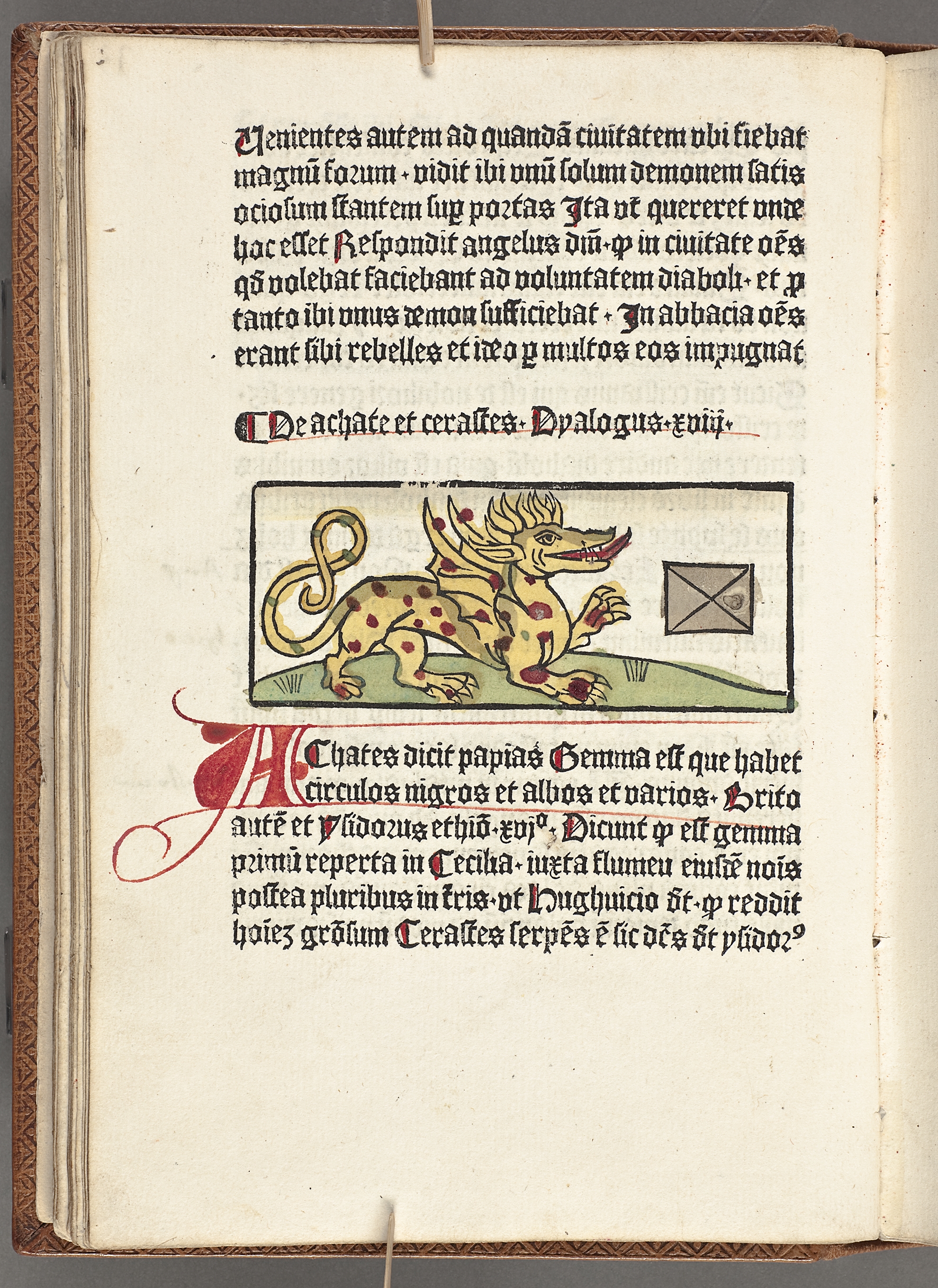 Old book page with gothic writing. In the middle is a dragon with his tongue outside his mouth.