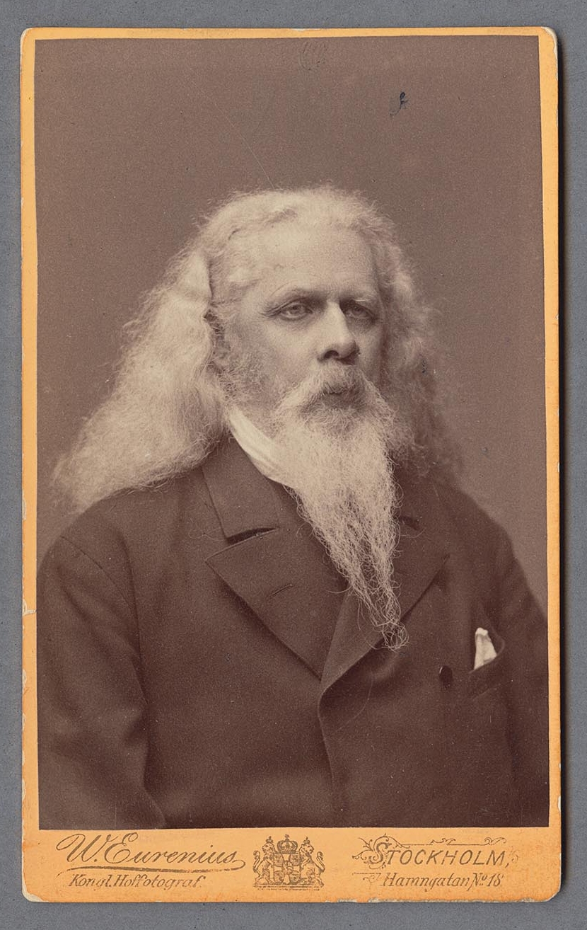 Black and white portrait of man with long white hair and beard.