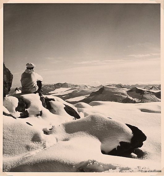 Person som sitter i snön på ett berg